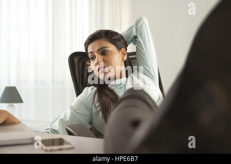 Porträt einer Geschäftsfrau am Schreibtisch mit ihren Füßen auf und arbeiten auf einem laptop Stockfoto