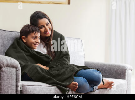 Lächelnde Mutter und Sohn in Fernsehen auf dem Sofa im Wohnzimmer Decke gehüllt Stockfoto