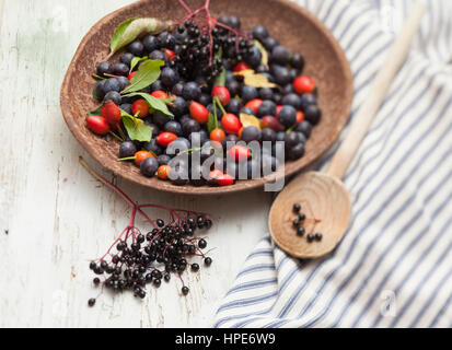 Hecke Früchte auf Zinn Untertasse mit gestreiften Schürze und Kochlöffel Stockfoto