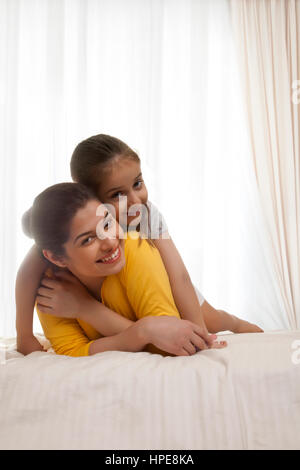 Tochter, die am Anfang ihrer Mutter im Bett liegend Stockfoto