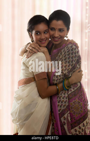 Teenager-Tochter in Sari umarmt Mutter lächelnd Stockfoto