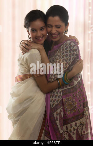 Lächelnde Teenager-Tochter in Sari und Mutter umarmt Stockfoto