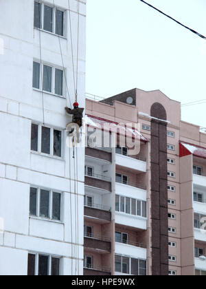 Industriekletterer in Helm und einheitliche Spachteln Wand auf Höhe. Riskante Aufgabe. Extreme Arbeit. Arbeitskraft Alpinist. Stockfoto