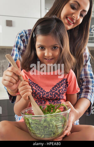 Mutter und Tochter bereitet frischen Salat in Küche Stockfoto