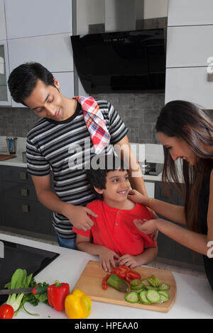 Die Eltern an ihren Sohn Schneiden von Gemüse in der Küche Stockfoto