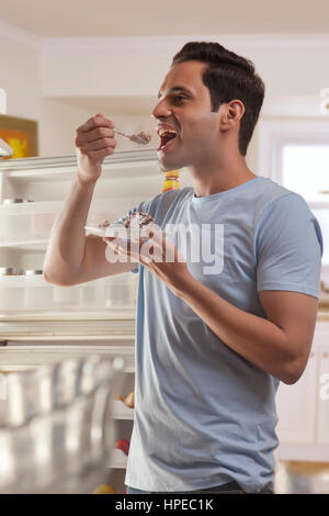 Junger Mann stehen vor offenen Kühlschrank Essen Gebäck Stockfoto