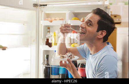 Nahaufnahme der junge Mann stand vor offenen Kühlschrank Essen Gebäck Stockfoto