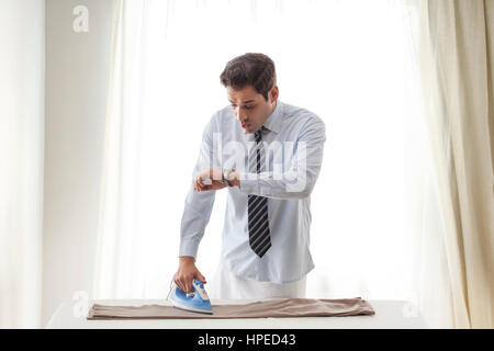 Geschäftsmann Hose bügeln und mit Blick auf die Armbanduhr Stockfoto