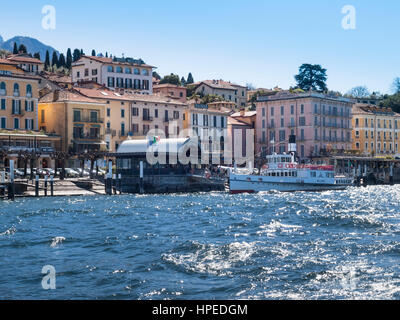 Bellagio der Comer See, Italien - 1. April 2015: Dock von Bellagio mit historischen Häusern des 19. Jahrhunderts. Ein PKW-Boot-Service auf dem See approachin Stockfoto