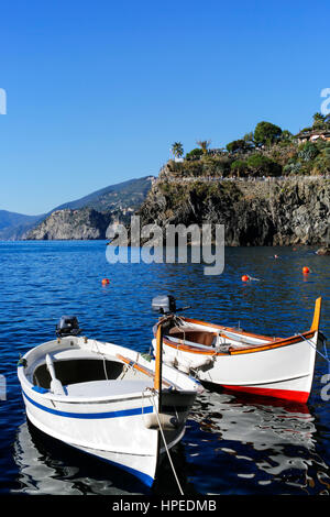 Zwei kleine Angelboote/Fischerboote verankert und schwimmend in einem ruhigen blauen Meer in der Nähe des Küste von Manarola, Cinque Terre, Italiens. Stockfoto