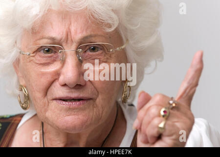 Model Release, Seniorin Mit Erhobenem Zeigefinger - ältere Frau mit erhobenen Zeigefinger Stockfoto