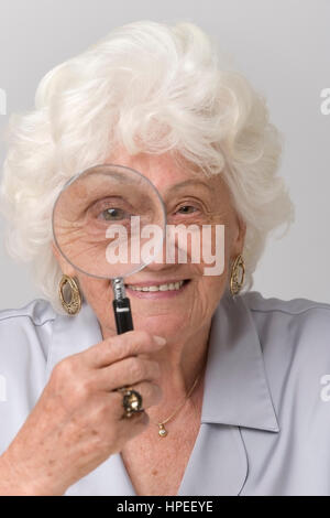 Model Release, Seniorin Schaut Durch Lupe - ältere Frau, die gerade durch eine Lupe Stockfoto