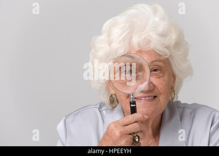 Model Release, Seniorin Schaut Durch Lupe - ältere Frau, die gerade durch eine Lupe Stockfoto