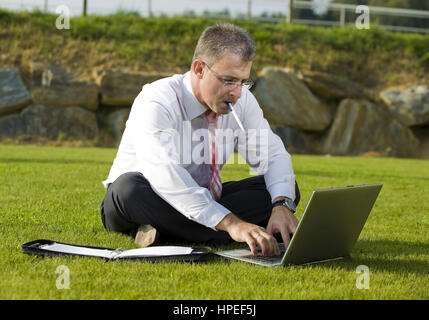 Model Release, Geschaeftsmann Sitzt Mit Laptop in der Wiese - Geschäftsmann in der Wiese sitzen und mit laptop Stockfoto