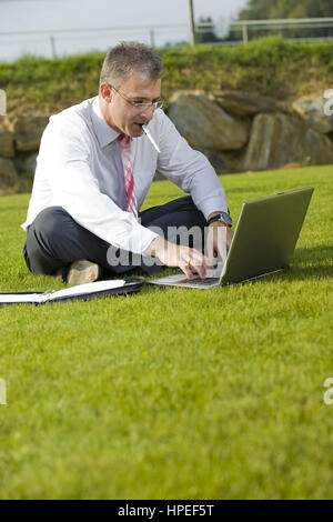 Model Release, Geschaeftsmann Sitzt Mit Laptop in der Wiese - Geschäftsmann in der Wiese sitzen und mit laptop Stockfoto