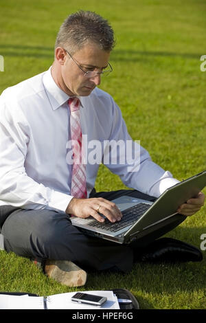 Model Release, Geschaeftsmann Sitzt Mit Laptop in der Wiese - Geschäftsmann in der Wiese sitzen und mit laptop Stockfoto