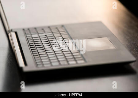 Geöffneten Laptop-Computer auf einem Schreibtisch aus Holz. Touchpad, Hintergrundbeleuchtung, keine Menschen im Fokus Stockfoto