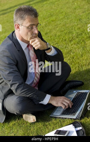 Model Release, Geschaeftsmann Sitzt Mit Laptop in der Wiese - Geschäftsmann in der Wiese sitzen und mit laptop Stockfoto