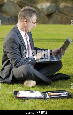 Model Release, Geschaeftsmann Sitzt Mit Laptop in der Wiese - Geschäftsmann in der Wiese sitzen und mit laptop Stockfoto