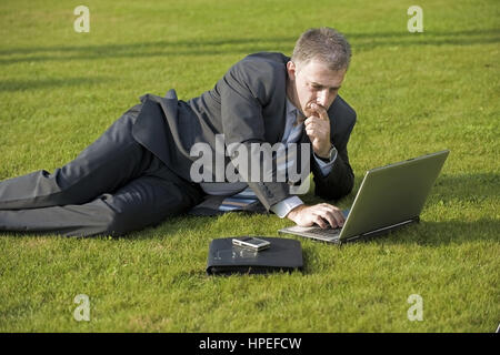 Model Release, Geschaeftsmann Sitzt Mit Laptop in der Wiese - Geschäftsmann in der Wiese sitzen und mit laptop Stockfoto