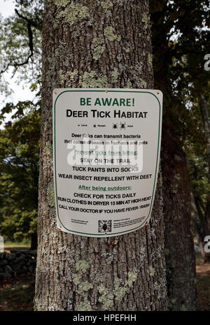 Ein Hirsch Zecke Warnzeichen auf einem Baum im Minute Man National Historical Park, Middlesex County, Massachusetts, USA. Stockfoto