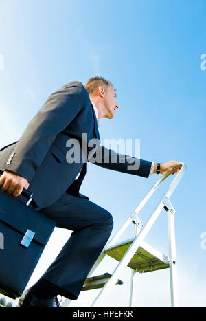 Model Release, Karrieremann Auf der Leiter, Symbolbild Karriereleiter - Geschäft Karriere, Geschäftsmann auf der Karriereleiter Stockfoto