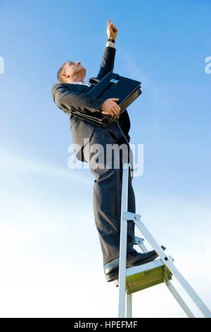 Model Release, Karrieremann Auf der Leiter, Symbolbild Karriereleiter - Geschäft Karriere, Geschäftsmann auf der Karriereleiter Stockfoto