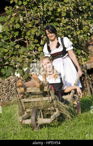 Zwei Junge Frauen Im Dirndl Mit Schubkarre - Frauen im Dirndl mit Schubkarre Stockfoto