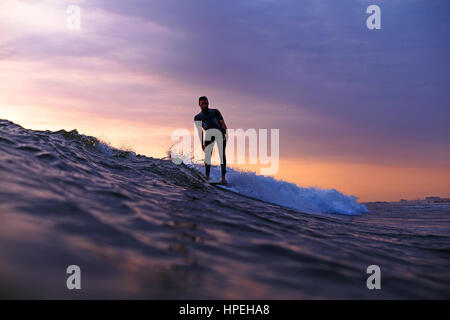 Surfer auf einer Welle eine Manöver bei Sonnenuntergang zu tun Stockfoto