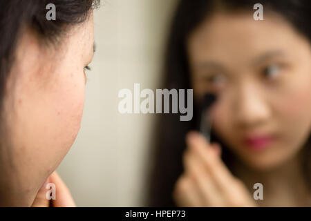 Chinesische Jugendliche setzen auf Make-up mit Pinsel vor Spiegel
