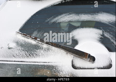 Der Wischer auf der Heckscheibe des Wagens nach der Fahrt auf einer verschneiten Straße. Stockfoto