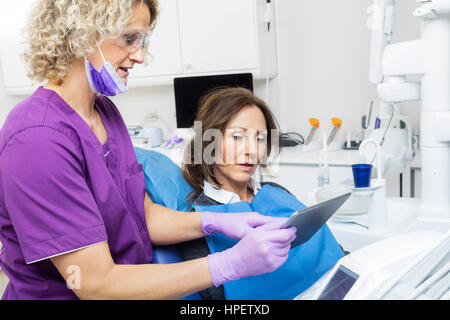 Assistentin zeigt Bericht Patienten auf digital-Tablette in der Zahnmedizin Stockfoto