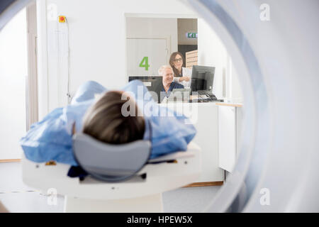 Männlichen und weiblichen Arzt ist mit dem Computer beim Patienten eine CT-Untersuchung im Krankenhaus Stockfoto