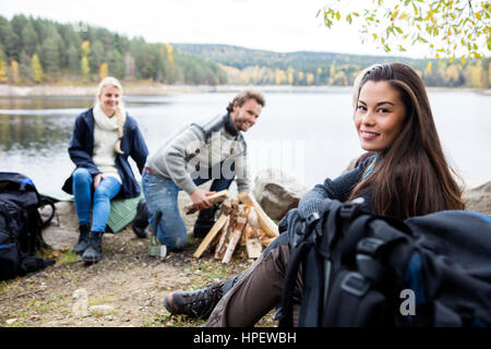 Porträt der jungen Frau mit Freunden Vorbereitung Lagerfeuer am Seeufer Stockfoto