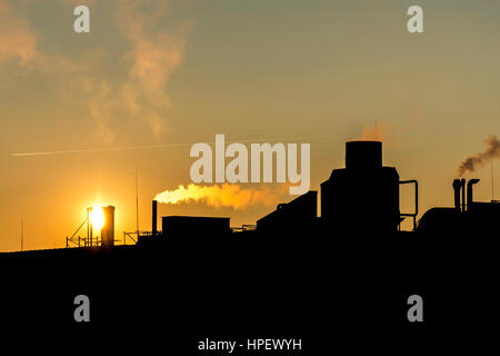 Silhuette Industriebetrieb Rauch aus Schornsteinen über einen farbenfrohen Sonnenuntergang Himmel Industrie Stockfoto