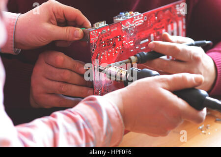 Nahaufnahme von Händen zwei Arbeiter Motherboard Löten Stockfoto