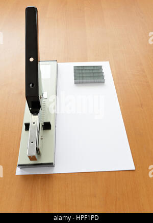 Hefter und Heftklammern mit Papier auf Holz Tisch Stockfoto