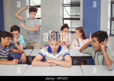 Schulfreunde Mobbing einen traurigen jungen im Unterricht in der Schule Stockfoto