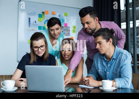 Lächelnde Geschäftsleute Diskussion über Laptop im Büro Stockfoto