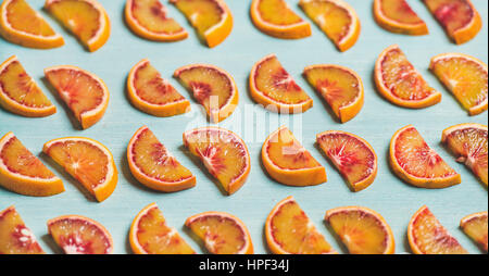 Natürliche Frucht Muster Konzept. Frische saftige Blutorange Scheiben über Leuchttisch blau bemalten Hintergrund, selektiven Fokus in Reihen gelegt. Stockfoto