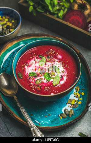 Detox rot-rote Bete-Suppe mit Minze, Chia, Flachs und Kürbis Samen in blauen Keramikschale über grauen Beton Hintergrund im Frühjahr. Abnehmen, reinigen Sie, Essen, vega Stockfoto