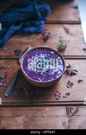 Heidelbeere Acai Smoothie Schüssel belegt mit Heidelbeeren, Kokosraspeln und Kakaonibs auf rustikalen Holztisch Stockfoto