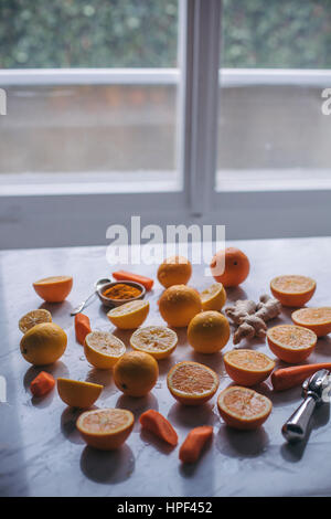 Frische Orange, Karotte, Zitrone, Ingwer und Kurkuma Pulver auf einem weißen Marmor Tisch Stockfoto