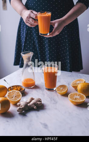 Frau mit einem Glas Orange, Zitrone und Karotten-Saft mit Kurkuma und Ingwer Stockfoto