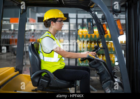 Weibliche Fabrikarbeiter fahren Gabelstapler in Fabrik Stockfoto