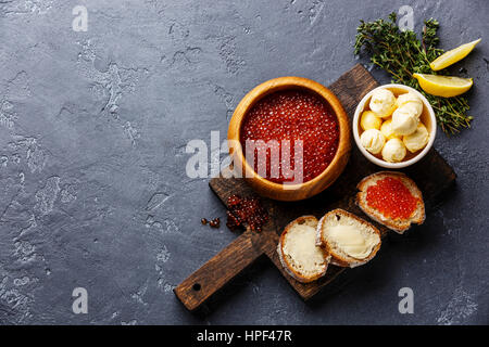Lachs rot Kaviar in Holzschale und Sandwiches auf dunklem Stein Textfreiraum Stockfoto
