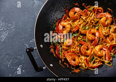 Stir-Fry Udon-Nudeln mit Garnelen in Wok-Pfanne auf dunklen Stein Hintergrund hautnah Stockfoto