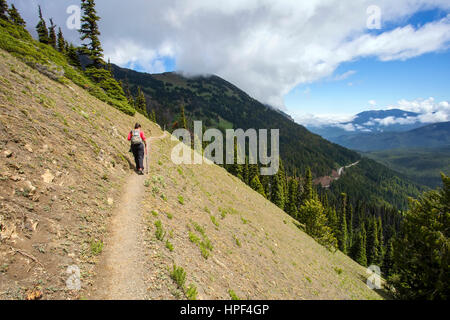 Eine weibliche Wanderer auf einem schmalen Bergrücken mit einem Pol Wandern zu Fuß entfernt von der Kamera. Stockfoto