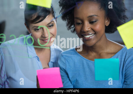Weibliche Grafiker Lesen von Text auf dem Glas im Kreativbüro Stockfoto