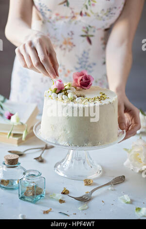 Frau ist einen chiffon Kuchen auf Marmor Tisch dekorieren Stockfoto